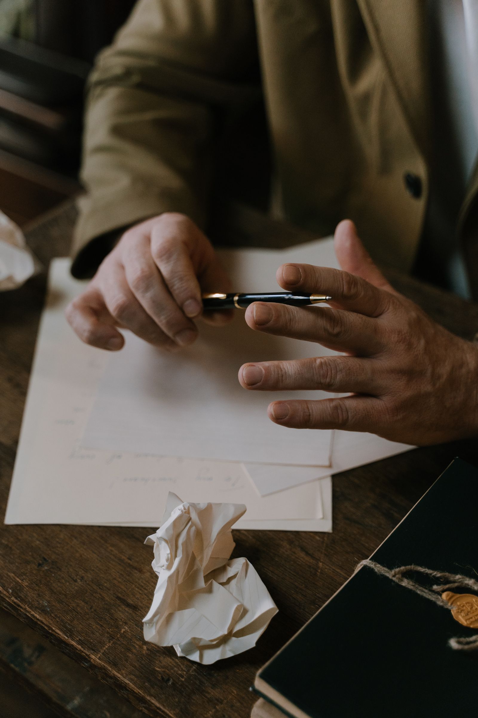 A writer drafting at a desk with pen and manuscript pages